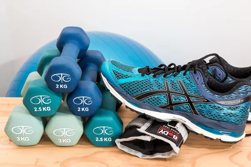 Hantlar, en pilatesboll och ett par träningsskor på en bänk